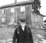 Adel Zetterholm framför sitt stora gråa hus